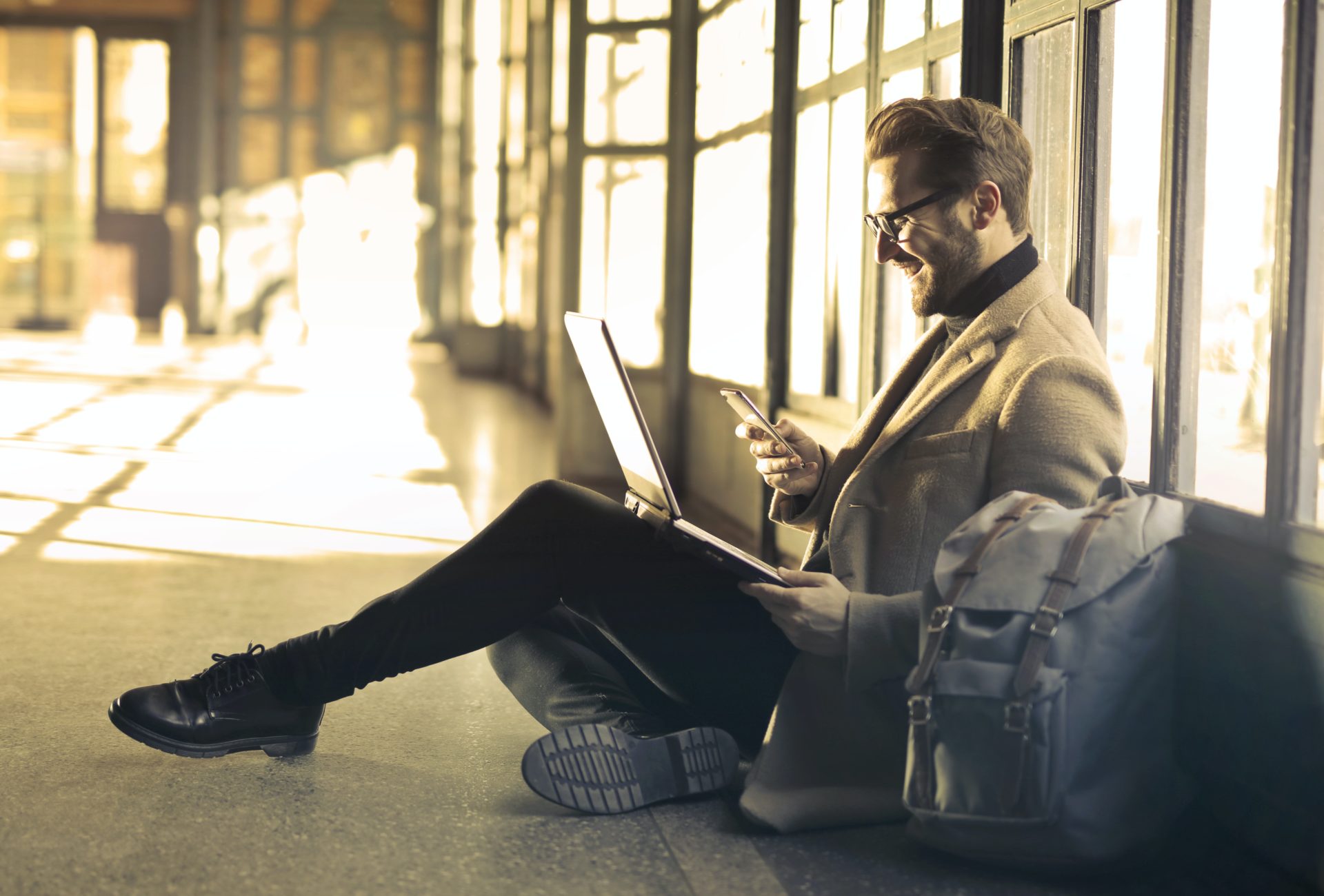 Man sitting with computer and phone in hand